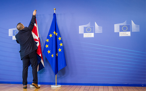 An EU official hangs the Union Jack next to the European Union flag at the VIP entrance at the European Commission headquarters in Brussels on Tuesday, Feb. 16, 2016. British Prime Minister David Cameron is visiting EU leaders two days ahead of a crucial EU summit. (AP Photo/Geert Vanden Wijngaert)