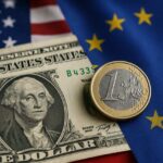 Una banconota da 1 dollaro e una moneta da 1 euro con la bandiera degli Usa e la bandiera dell'UE sullo sfondo